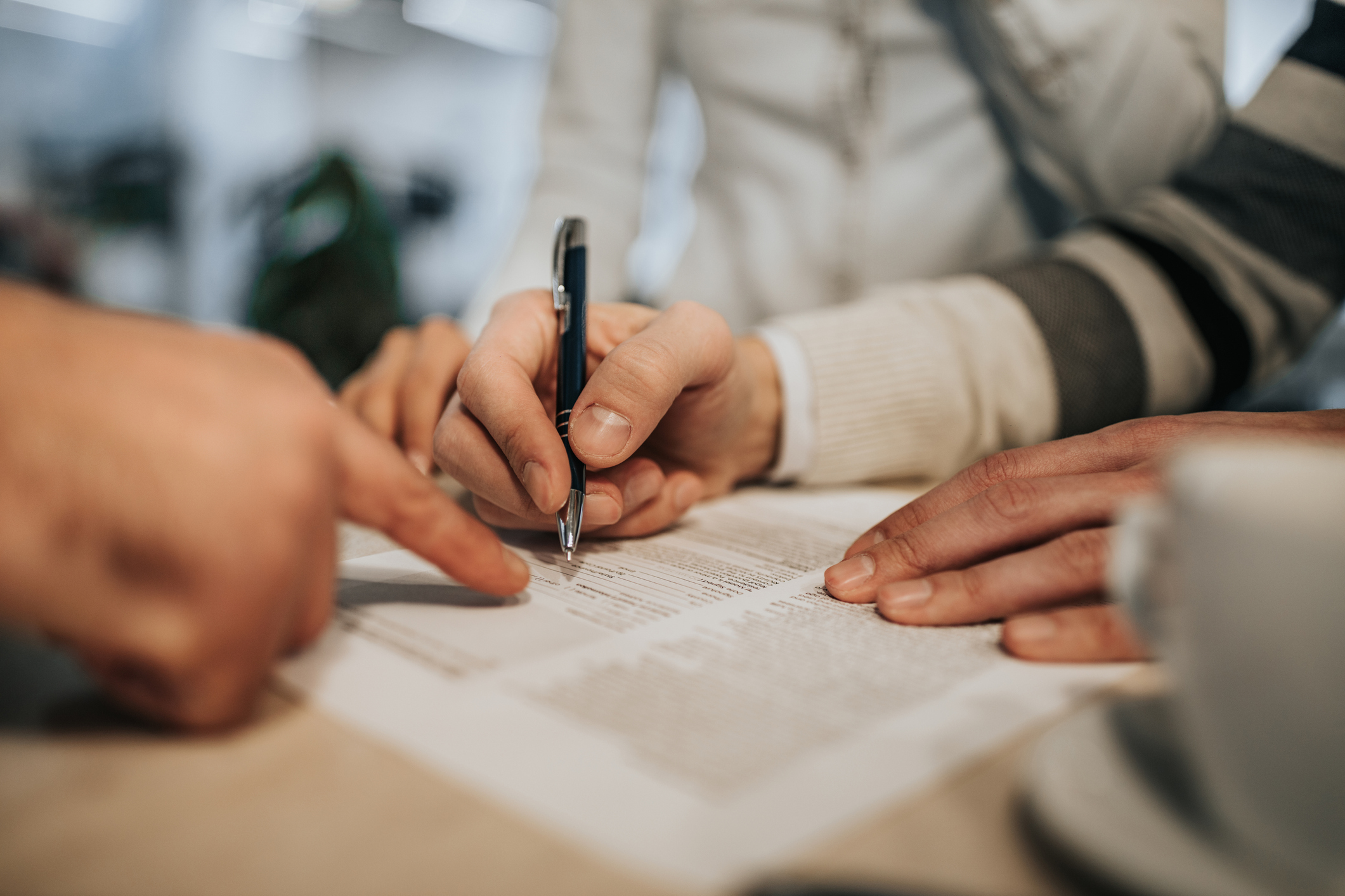 One person writing on a page, another pointing at a line on the page